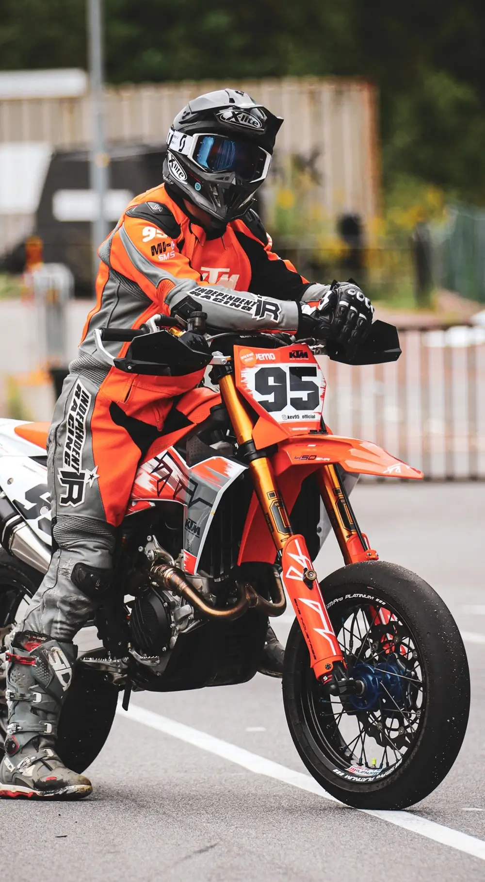 Förare med orange skinnställ pa Supermoto motorcykel.